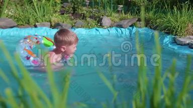 孩子在一个小池塘里的充气圈里游泳。 园区，花草环湖.. 快乐